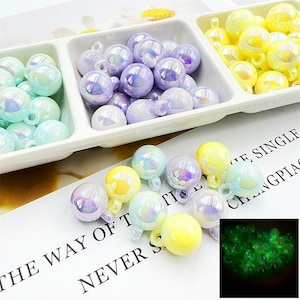 May include: Assortment of iridescent glass beads in pastel colours, including light blue, lavender, and yellow. The beads have a pearlescent finish and are designed to glow in the dark. The text "The Way of The Time Never Stops" is visible in the image.