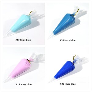 May include: Four piping bags filled with different coloured frosting. The bags are labelled with numbers and colours, including #17 Mint blue, #18 Haze blue, #19 Haze blue, and #20 Haze blue.