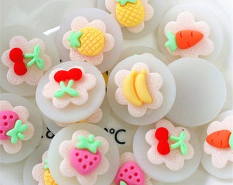 May include: Assortment of colorful fruit and vegetable shaped resin embellishments. Each embellishment is a different fruit or vegetable, including a pineapple, strawberry, cherry, banana, carrot, and a few others. The embellishments are all on a white background.