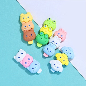 May include: A set of colorful, cartoon animal-shaped hair clips. The clips are stacked in groups of three and feature characters like a frog, a bear, a cat, and a dog.