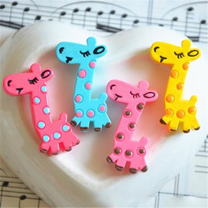 May include: Four colourful giraffe figurines with polka dots. The giraffes are pink, blue, yellow, and brown. They are made of plastic and have a cartoonish style.