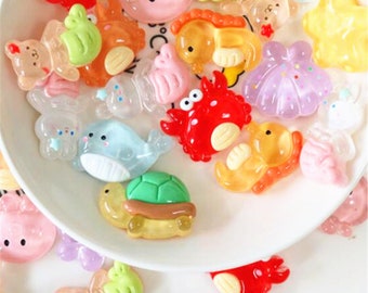 May include: Assortment of colourful resin sea creature charms. The charms include a crab, a turtle, a seahorse, a whale, a starfish, a clam, and a variety of other sea creatures.