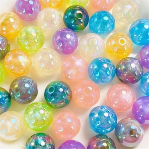 May include: Assortment of iridescent round beads in various pastel colors, including pink, blue, green, yellow, and purple. The beads have a speckled, textured surface.