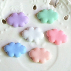 May include: Six pastel-colored cloud shaped resin charms. The charms are in shades of purple, green, white, pink, and blue.
