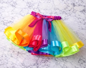 Tutù in tulle arcobaleno, con bordi in nastro colorato, ideale come costume per giocare o regalo di compleanno.