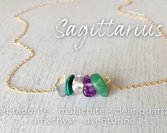 May include: Gold necklace with a labradorite, malachite, clear quartz, amethyst, and aventurine stone charm. The necklace is labeled "Sagittarius".
