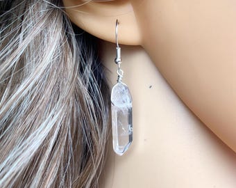 Puede incluir: Pendientes de plata con un colgante de cristal de cuarzo transparente. El cristal está facetado y tiene una punta puntiaguda.