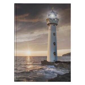 May include: A white lighthouse with a light on top stands on a rocky outcropping. The lighthouse is surrounded by blue water with waves crashing against the rocks. The sky is a soft orange and pink, with clouds in the background.