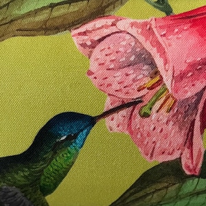 May include: A close-up of a vibrant textile print featuring a hummingbird and a pink flower. The hummingbird has a blue head and green body, with a long beak reaching into the flower. The background is a light green color.