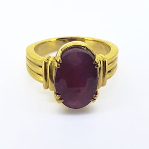 May include: A gold ring featuring a large, oval-shaped, dark purple gemstone set in a gold claw setting.