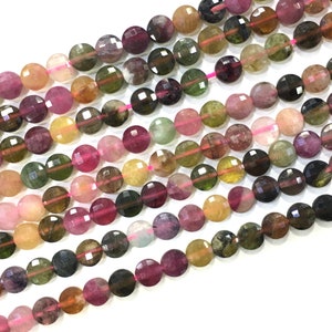 May include: A strand of faceted round beads made of multi-colored watermelon tourmaline. The beads are approximately 6mm in diameter and have a variety of colors, including pink, green, yellow, and brown.