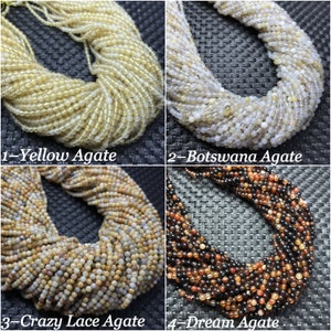 Puede incluir: Cuatro hebras de cuentas de ágata en diferentes colores y patrones. Las cuentas son redondas y lisas. Los colores son amarillo, blanco, marrón y rojo. Las cuentas están etiquetadas como "Ágata Amarilla", "Ágata de Botsuana", "Ágata Crazy Lace" y "Ágata Sueño".