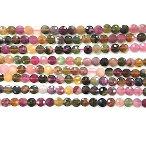 May include: A strand of multi-colored round gemstone beads. The beads are a mix of pink, green, yellow, and brown. The beads are faceted and have a smooth, polished finish.