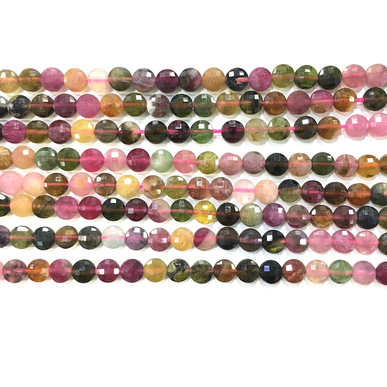 May include: A strand of multi-colored round gemstone beads. The beads are a mix of pink, green, yellow, and brown. The beads are faceted and have a smooth, polished finish.