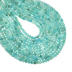 Può includere: Una collana di perle di acquamarina blu chiaro. Le perle sono sfaccettate e hanno una forma rotonda. Le perle sono infilate su un filo trasparente.