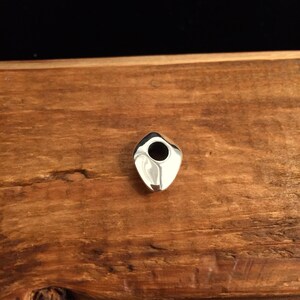 Op de afbeelding: Een zilveren hanger met een gladde, afgeronde, traanvormige vorm en een gat in het midden.