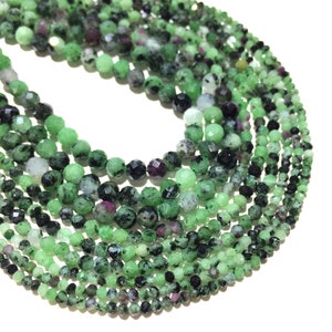 May include: A strand of green, black, and pink gemstone beads. The beads are faceted and have a rough, natural texture.
