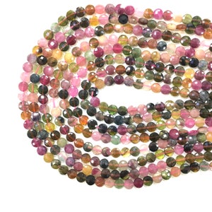 May include: A strand of round, faceted, multi-colored tourmaline beads. The beads are a mix of pink, green, brown, and yellow.