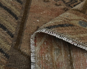 May include: Close-up of a brown and beige rug with a geometric pattern. The rug has a fringe border and is woven with a variety of textures.