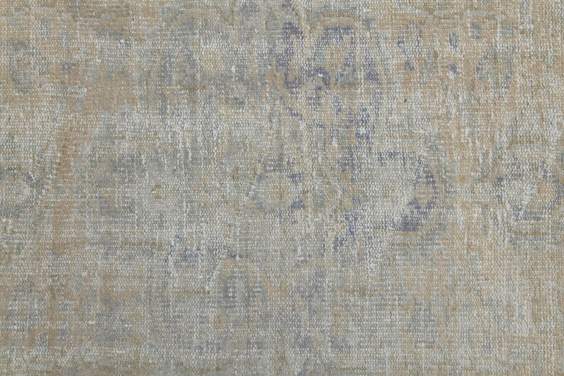 May include: A close-up of a textured fabric with a faded blue and brown pattern. The fabric has a worn and vintage look.
