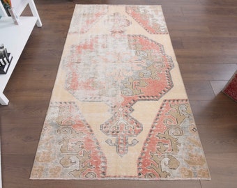 May include: A vintage style rug with a faded, distressed look. The rug has a cream background with a geometric pattern in shades of pink, brown, and gray.