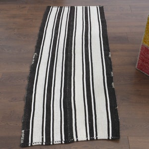 May include: A black and white striped runner rug with a woven texture. The rug is approximately 2.5 feet wide and 6 feet long.