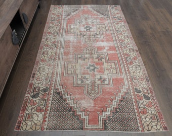 Puede incluir: Una alfombra vintage con un fondo rojo descolorido y intrincados patrones geométricos en blanco y negro. La alfombra tiene un aspecto desgastado y un borde deshilachado.