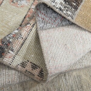 Könnte beinhalten: Nahaufnahme eines gewebten Teppichs in Beige und Braun mit einem Muster. Der Teppich ist umgeklappt, sodass die Unterseite des Stoffes sichtbar ist.