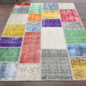 May include: A colourful patchwork rug featuring a range of colours and patterns, including green, blue, red, yellow, and purple. The rug is made from recycled materials and has a distressed appearance.
