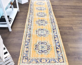 May include: A yellow and blue patterned runner rug with a floral design. The rug has a distressed look and is made of a soft, woven material.