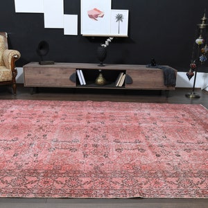 May include: A vintage pink and black patterned rug with a faded look. The rug has a geometric design with a central medallion and a border.