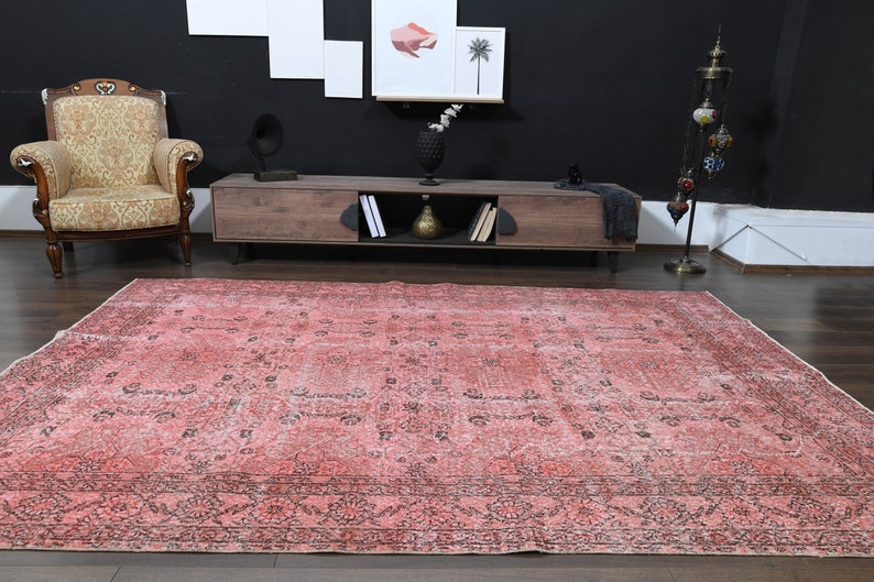 May include: A vintage pink and black patterned rug with a faded look. The rug has a geometric design with a central medallion and a border.