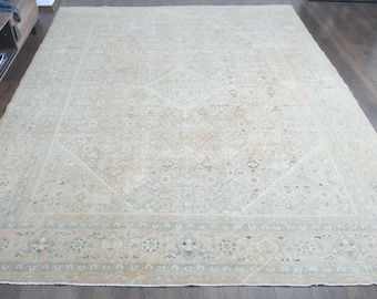 May include: A large rectangular area rug featuring a neutral beige and cream color palette with intricate, faded floral and geometric patterns. The design includes a central medallion motif surrounded by a detailed border with repeating motifs.