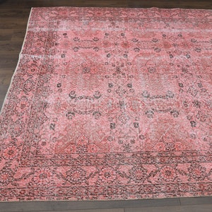 May include: A vintage pink and black patterned rug with a floral design. The rug has a faded look and is made of a soft, woven material.