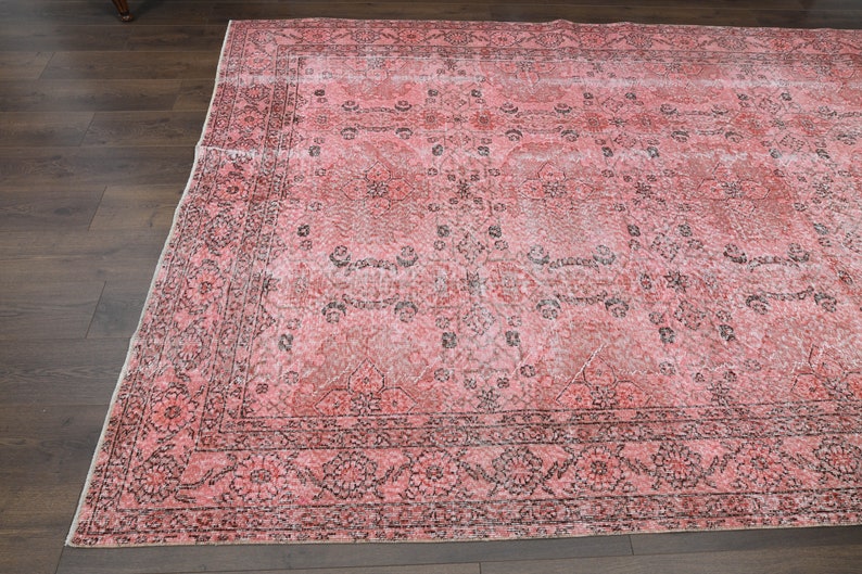 May include: A vintage pink and black patterned rug with a floral design. The rug has a faded look and is made of a soft, woven material.