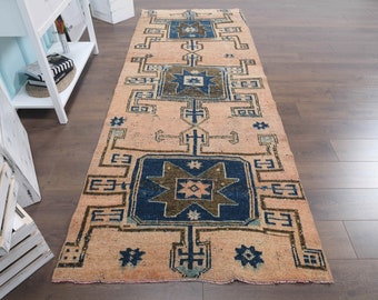May include: A vintage runner rug with a peach background and a geometric pattern in shades of blue, brown, and white.