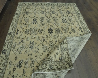May include: A beige rug with a black and white floral pattern. The rug is folded in half and the edges are visible.