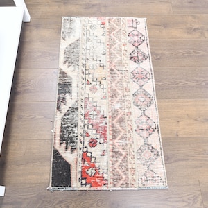 Könnte beinhalten: Ein Vintage-Teppich mit geometrischem Muster in Rot-, Schwarz- und Weißtönen. Der Teppich hat einen Used-Look und ist aus weichem, gewebtem Material gefertigt.