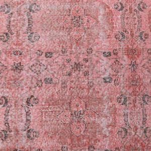 May include: A vintage-style rug with a faded pink background and intricate black floral patterns. The rug has a distressed look, giving it a unique and antique feel.