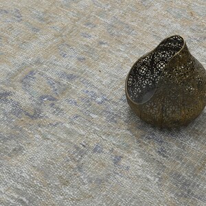 May include: A decorative metal candle holder with a delicate, intricate design. The holder is made of a light gold metal and has a rounded, organic shape.