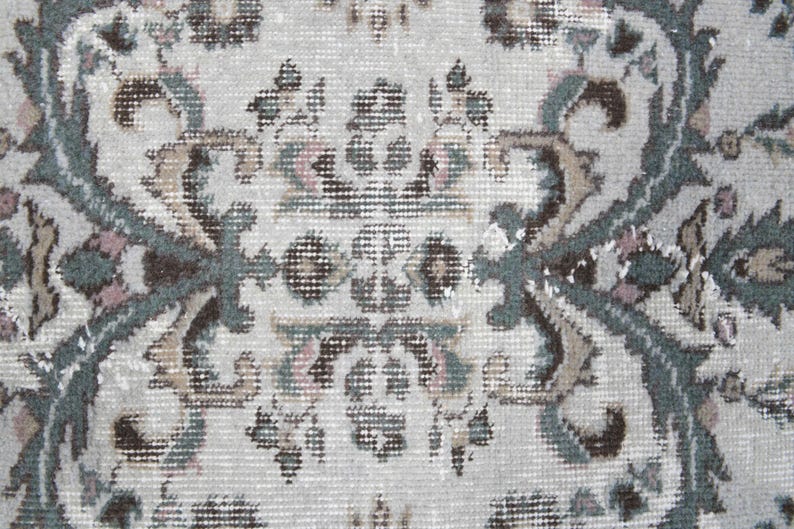 May include: Close-up of a cream-colored rug with a detailed floral pattern in shades of brown, green, and pink.