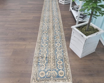 May include: A long, narrow rug with a blue and cream floral pattern. The rug has a distressed look and is made of a soft, woven material.