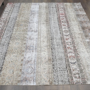 May include: A rectangular, distressed-look rug with a faded, vintage aesthetic. The rug features vertical stripes in shades of beige, gray, and muted red, with floral and geometric patterns. The rug is suitable for a living room or bedroom.