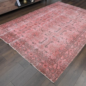 May include: A vintage pink and black area rug with a floral pattern. The rug has a faded, distressed look and is perfect for adding a touch of bohemian style to any room.