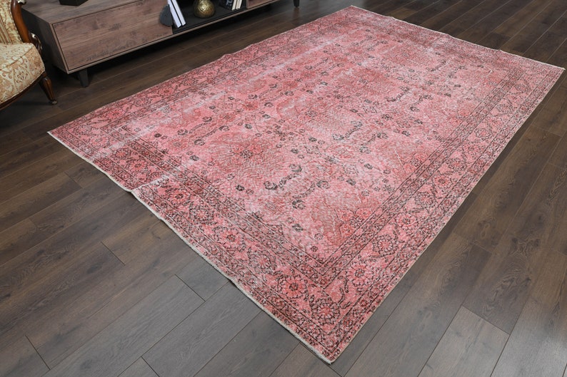 May include: A vintage pink and black area rug with a floral pattern. The rug has a faded, distressed look and is perfect for adding a touch of bohemian style to any room.