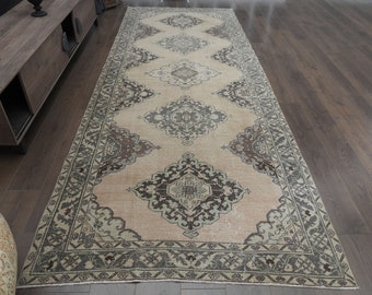 May include: A vintage cream-colored rug with a detailed floral pattern in shades of brown and gray. The rug has a border with a repeating geometric design.
