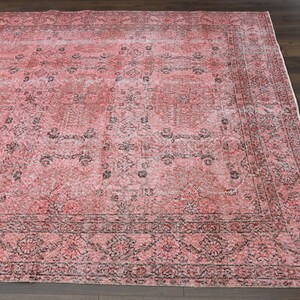 May include: A vintage pink and black area rug with a floral pattern. The rug has a distressed look and is made of a soft, durable material.