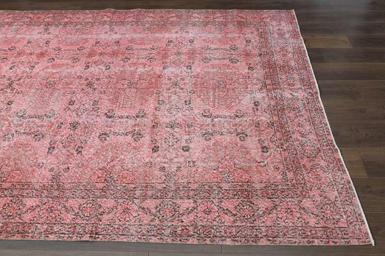 May include: A vintage pink and black area rug with a floral pattern. The rug has a distressed look and is made of a soft, durable material.