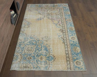 May include: A vintage rug with a light beige background and a blue and brown floral pattern. The rug has a faded, distressed look, giving it a unique and antique feel.