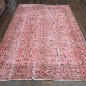 May include: A vintage pink and black patterned rug with a faded look. The rug has a floral design and a border.
